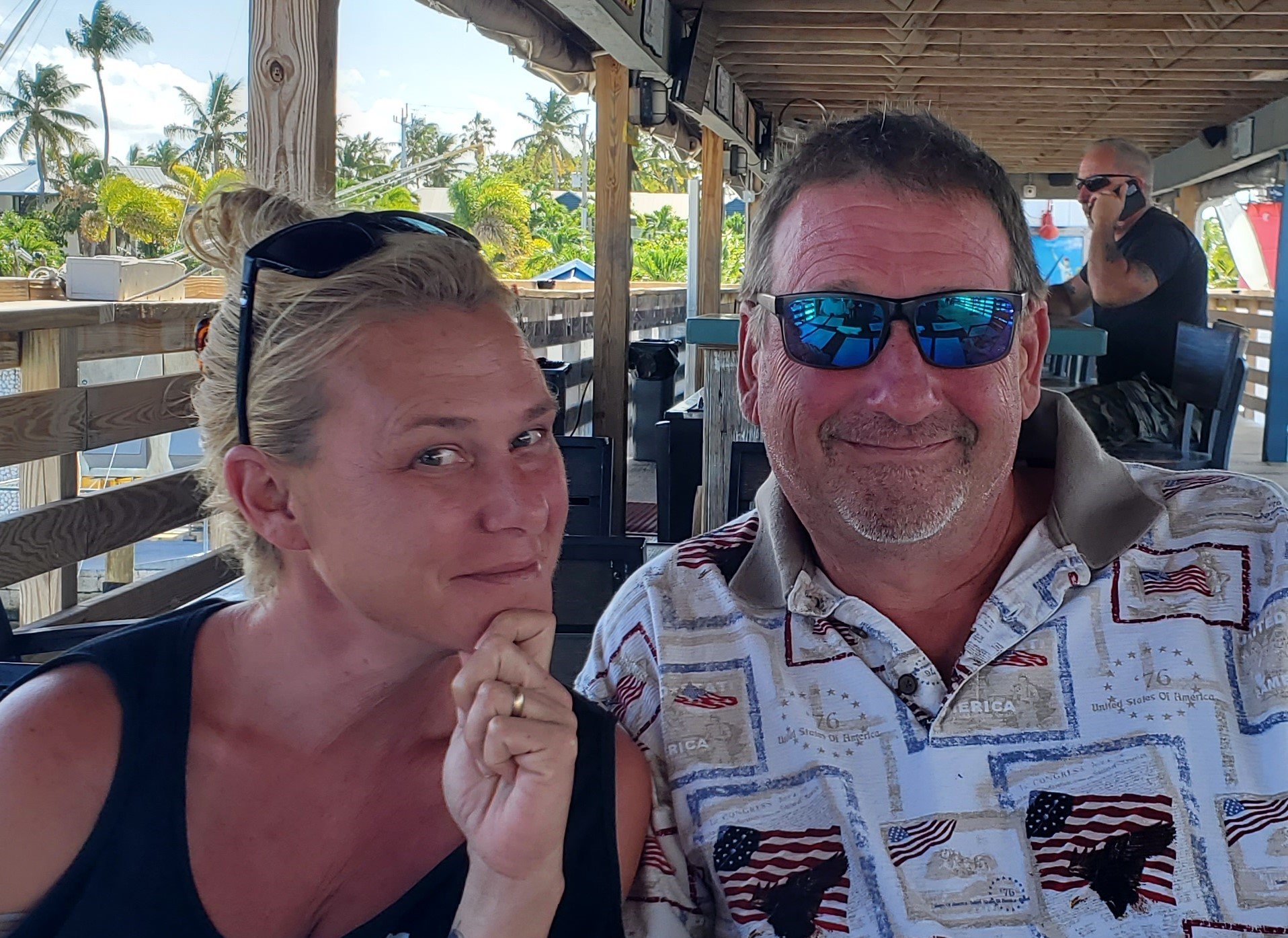 Meg Ozbirn - Co-Founder enjoying the coastal lifestyle at a waterfront restaurant with tropical palm trees in Southwest Florida